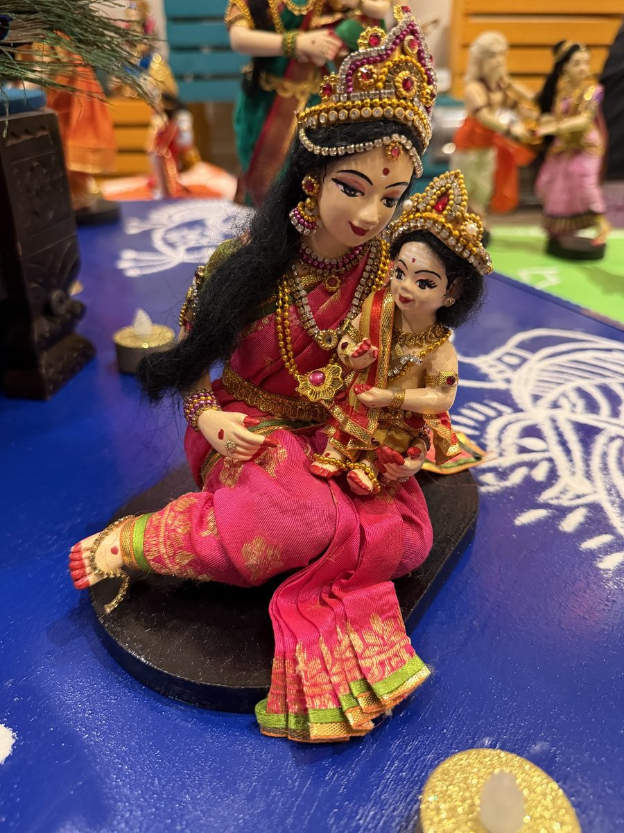 Golu doll of a Karthigai maiden in a pink sari, seated, with baby Murugan on her lap