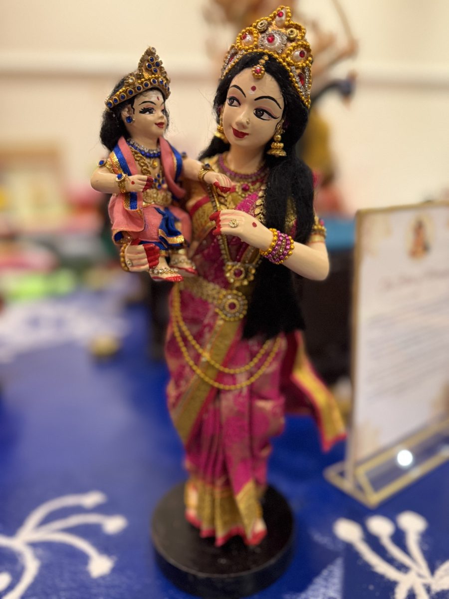 Golu doll of a Karthigai maiden in a pink and gold sari carrying baby Murugan
